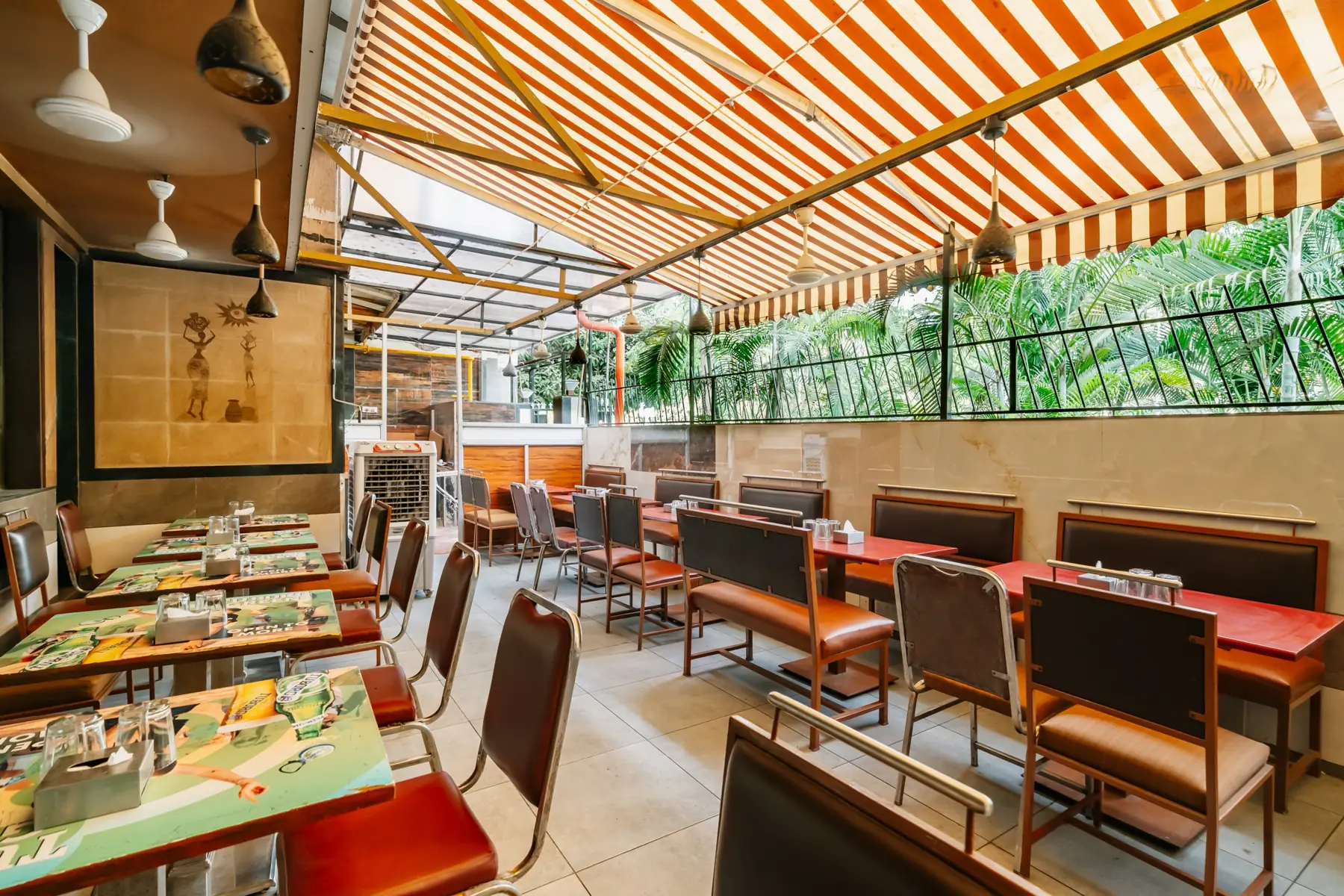 The Park View dining room under a striped awning, with red tables and leather chairs