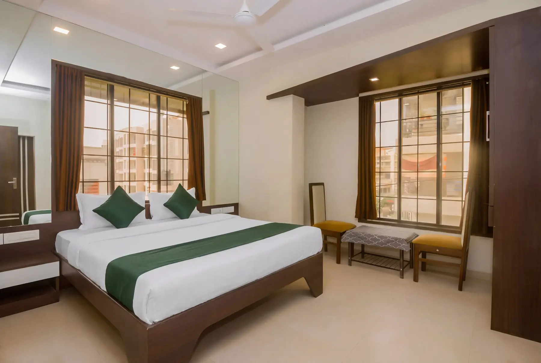 A double room with a wide window and green bed runner